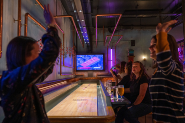 Two friends high-fiving during a game of Electric Shuffleboard.