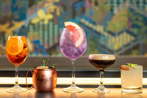 Group selection of cocktails featuring The Aperosé Spritz, Notorious F.I.G. Mule, Indigo Elderflower G&T, Salted Carmel Espresso Martini, and the Spicy Lucy