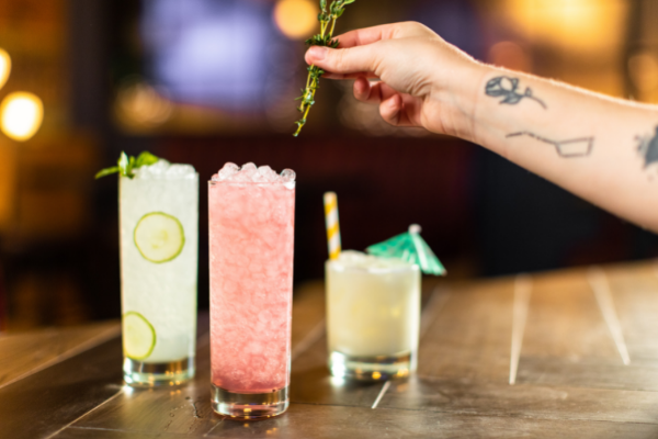 Collection of cocktails featuring a bartender adding a sprig of mint to the Watermelon Sugar Mojito.